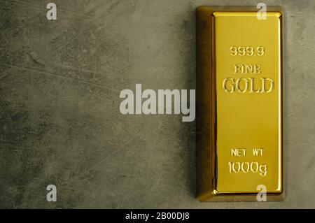 Masseln aus reinem Gold Metal bullion auf einem grauen strukturierten Hintergrund Stockfoto