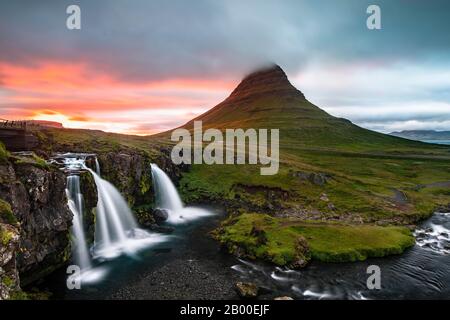 Wasserfall Kirkjufellsfoss und Berg Kirkjufell, Sonne bricht durch Wolken, Grunddarfjoerdur, Snaefellsnes Halbinsel, Snaefellsnes, Vesturland Stockfoto