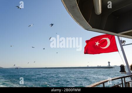 Die türkische Flagge winkt auf der Fähre. Möwen fliegen über die Fähre. Stockfoto