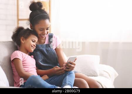 Afrikanische Teenager-Mädchen lehren, Handy ihrer Schwester zu zeigen Stockfoto