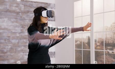 Schöne Innenarchitektin mit virtueller Reality-Brille in einer leeren Wohnung. Stockfoto