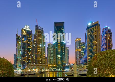 Dubai Marina und Hafen bei Sonnenuntergang - Beleuchtete moderne Türme am Abend, Vereinigte Arabische Emirate Stockfoto