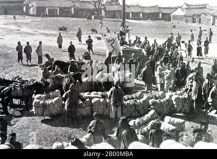 China: Eine Pu'er Baumwollkarawane unter der Qing Flagge im späten 19. Jahrhundert. Die Tea Horse Road (Cha Ma Dao) war ein Netzwerk von Maultierkarawanenwegen, die sich durch die Berge von Yunnan, Sichuan und Tibet im Südwesten Chinas schlängeln. Es wird auch manchmal als die Southern Silk Road und Ancient Tea and Horse Road bezeichnet. Seit etwa tausend Jahren war die Ancient Tea Route eine Handelsverbindung von Yunnan, einer der ersten Teeanbauregionen, nach Indien über Burma, nach Tibet und über die Provinz Sichuan nach Zentralchina. Neben Tee trugen die Maultierkarawanen Salz. Stockfoto