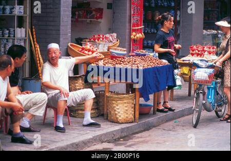 China: Ein Hui-Walnussverkäufer weist den Weg auf eine belebte Straße im muslimischen Viertel Xi'an, Provinz Shaanxi. XI'an ist die Hauptstadt der Provinz Shaanxi und eine Provinzstadt in der Volksrepublik China. Eine der ältesten Städte in China, mit mehr als 3,100 Jahren Geschichte, die Stadt war bekannt als Chang'an vor der Ming-Dynastie. XI'an ist eine der vier großen antiken Hauptstädte Chinas, die diese Position unter mehreren der wichtigsten Dynastien der chinesischen Geschichte innehatte, darunter Zhou, Qin, Han, Sui und Tang. XI'an ist die östliche Endstation der Seidenstraße. Stockfoto