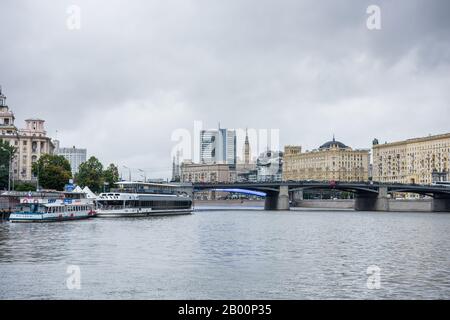 Historische Gebäude und am Flussufer sowie eine Brücke über den Moskwa-Fluss, Moskau, Russland. Ansicht bilden Sie ein Kreuzfahrtschiff auf dem Fluss. Stockfoto