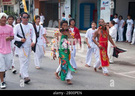 Thailand: Ein entrückter Anhänger oder "Ma Song" nimmt an einer Prozession durch Phuket Town, Phuket Vegetarian Festival, Teil. Das Vegetarische Festival ist ein religiöses Festival, das jährlich auf der Insel Phuket im Süden Thailands stattfindet. Es zieht Massen von Zuschauern wegen vieler der ungewöhnlichen religiösen Rituale an, die durchgeführt werden. Viele religiöse Anhänger werden sich mit Schwertern niederschlagen, ihre Wangen mit scharfen Gegenständen durchbohren und andere schmerzhafte Handlungen begehen. Stockfoto