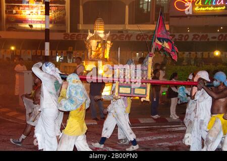 Thailand: Schreinträger Rennen durch die Straßen in der Nachtsparade, Phuket Vegetarian Festival. Das Vegetarische Festival ist ein religiöses Festival, das jährlich auf der Insel Phuket im Süden Thailands stattfindet. Es zieht Massen von Zuschauern wegen vieler der ungewöhnlichen religiösen Rituale an, die durchgeführt werden. Viele religiöse Anhänger werden sich mit Schwertern niederschlagen, ihre Wangen mit scharfen Gegenständen durchbohren und andere schmerzhafte Handlungen begehen. Stockfoto