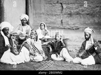 Afghanistan: Drei nautch Mädchen mit Musikern, aufgenommen in Kabul in Afghanistan von John Burke (1843-1900), c. 1879-1880. Das Wort Nautch ist eine englischsprachige Version von nāc, ein Wort, das in Hindi und Urdu und mehreren anderen Sprachen von Nordindien gefunden wird, abgeleitet vom Sanskrit, Nritya, über das Prakrit, Nachcha. Eine einfache und wörtliche Übersetzung von Nautch ist 'Tanz' oder 'Tanz'. Die Kultur der darstellenden Kunst von Nautch stieg zu Prominenz während der späteren Periode des Moghul-Reiches und der East India Company Rule. Stockfoto