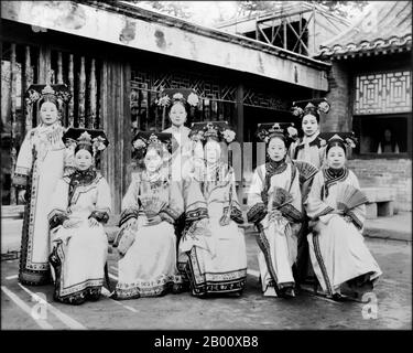 China: Mandschu Damen der Verbotenen Stadt Peking, c. 1910. Mandschu Frauen der Verbotenen Stadt oder Gugong in Peking posieren für ein Foto c. 1910 in den letzten Tagen der Mandschu Qing Dynastie (1644-1911). Sie tragen aufwendige und teure Kleider. Ihre Gesichter sind mit Puder getüncht, und ihr Lippenstift wird in einem schmalen Band über die Mitte ihrer Lippen nach der Mode der Zeit aufgetragen. Stockfoto