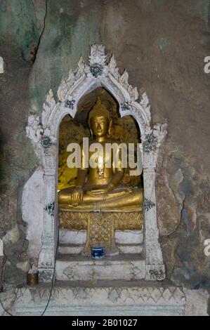 Thailand: Buddha in einer Nische in Tham Khao Luang, Phetchaburi. Tham Khao Luang ist eine große Höhle, die aus drei miteinander verbundenen Kammern besteht und sich durch viele hängende Stalaktiten und Buddha-Bilder auszeichnet, einschließlich eines phra non oder liegenden Buddha. Das Hauptbronzebild wurde auf Befehl von König Chulalongkorn (Rama V) gegossen und seinen berühmten Vorgängern, den Königen Rama III. Und Rama IV., gewidmet Es gibt eine natürliche Öffnung in der Decke der zweiten, Hauptkammer, durch die Tageslicht strömt und die Bilder im Inneren erhellt. Stockfoto