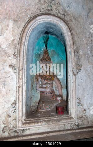 Thailand: Buddha in einer Nische in Tham Khao Luang, Phetchaburi. Tham Khao Luang ist eine große Höhle, die aus drei miteinander verbundenen Kammern besteht und sich durch viele hängende Stalaktiten und Buddha-Bilder auszeichnet, einschließlich eines phra non oder liegenden Buddha. Das Hauptbronzebild wurde auf Befehl von König Chulalongkorn (Rama V) gegossen und seinen berühmten Vorgängern, den Königen Rama III. Und Rama IV., gewidmet Es gibt eine natürliche Öffnung in der Decke der zweiten, Hauptkammer, durch die Tageslicht strömt und die Bilder im Inneren erhellt. Stockfoto