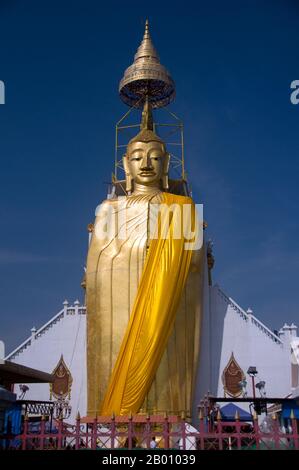 Thailand: Riesiger stehender Buddha, Wat Intharawihan, Bangkok. Das Hauptmerkmal von Bangkoks Wat Intharawihan ist der 32 Meter hohe stehende Buddha, der entweder Luang Pho To oder Phrasiariyametri genannt wird. Die Fertigstellung dauerte über 60 Jahre und ist mit Glasmosaiken und 24-Karat-Gold verziert. Der Knoten des Buddha-Bildes enthält ein Relikt von Lord Buddha aus Sri Lanka gebracht. Der Tempel wurde zu Beginn der Ayutthaya-Periode gebaut. Stockfoto