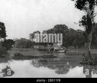 Thailand: Ein siamesischer Weiler auf einem Kanal in der Nähe des Chao Phraya Flusses, nördlich von Bangkok, c. 1900. Um die Wende des 20. Jahrhunderts waren die meisten Siamesen Reisbauern, die entlang der Wasserwege lebten und arbeiteten. Jeder Haushalt hatte ein Boot, von dem schätzungsweise 600,000 die Kanäle und Flüsse von Bangkok befuhren. Rudern wurde von der Rückseite des Bootes aus durchgeführt. Die meisten Häuser wurden aus Holz und Bambus gebaut und auf Stelzen mit einer Leiter zum Wasser gebaut. Stockfoto