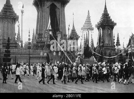 Thailand: Die Trauerprozession, die die Überreste von König Chulalongkorn trägt, geht dreimal um die Einäscherungsstelle, 1911. Kunstvolle Pavillons und buddhistische Tempel werden traditionell speziell für königliche Beerdigungen in Siam errichtet. Der Leichnam des Verstorbenen wurde einbalsamiert und bewahrt, während die Einäscherungsstätte errichtet wurde. Beerdigungsrituale und eine Trauerperiode könnten Monate oder sogar ein Jahr dauern, bevor die Beerdigung stattfand. Der einbalsamierte Körper wurde dann in einer knieenden Position in einer Goldurne auf einer hohen Bahre in einem kunstvollen Gebäude platziert, das eingeäschert werden sollte. Stockfoto