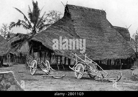 Thailand: Ochsenkarren liegen vor einem traditionellen reetgedeckten Holzhaus auf Stelzen im ländlichen Phitsanulok, Zentralthailand, c. 1900. Phitsanulok ist eine alte Stadt in den unteren Ebenen des nördlichen Thailands. Es war 25 Jahre lang Hauptstadt des Ayutthaya-Königreichs, von 1463 an nach einer Reihe birmanischer Invasionen. Obwohl Phitsanulok nicht weit im Norden liegt, waren die Bewohner der Region um die Wende des 20. Jahrhunderts den Zentralsiamesen als Laos bekannt. Stockfoto