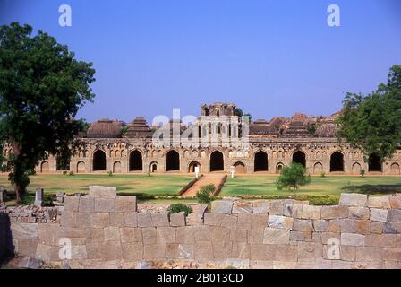 Indien: Elefantenställe, Hampi, Bundesstaat Karnataka. Die Elefantenställe wurden verwendet, um die zeremoniellen Elefanten des königlichen Haushalts zu beherbergen. Die Struktur zeigt einen deutlichen islamischen Einfluss in ihren Kuppeln und gewölbten Toren. Hampi ist ein Dorf im nördlichen Bundesstaat Karnataka. Es befindet sich in den Ruinen von Vijayanagara, der ehemaligen Hauptstadt des Vijayanagara-Reiches. Vor der Stadt Vijayanagara ist es weiterhin ein wichtiges religiöses Zentrum, in dem der Virupaksha-Tempel sowie mehrere andere Denkmäler der Altstadt untergebracht sind. Stockfoto