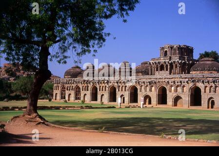 Indien: Elefantenställe, Hampi, Bundesstaat Karnataka. Die Elefantenställe wurden verwendet, um die zeremoniellen Elefanten des königlichen Haushalts zu beherbergen. Die Struktur zeigt einen deutlichen islamischen Einfluss in ihren Kuppeln und gewölbten Toren. Hampi ist ein Dorf im nördlichen Bundesstaat Karnataka. Es befindet sich in den Ruinen von Vijayanagara, der ehemaligen Hauptstadt des Vijayanagara-Reiches. Vor der Stadt Vijayanagara ist es weiterhin ein wichtiges religiöses Zentrum, in dem der Virupaksha-Tempel sowie mehrere andere Denkmäler der Altstadt untergebracht sind. Stockfoto