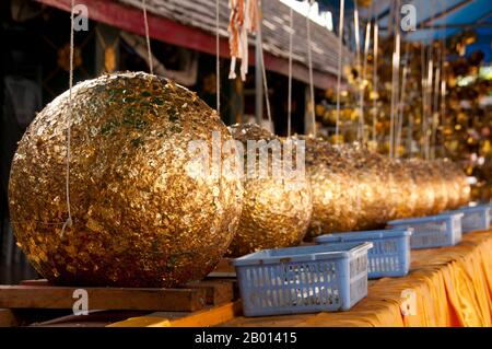 Thailand: Luk nimit (heilige Steinkugeln), bedeckt mit Blattgold und thailändischen Baht-Münzen, Wat Phrathat Doi Kham, Chiang Mai. Luk nimit sind Steinkugeln, die an den vier Ecken und an den vier Kardinalpunkten eines neuen Ukossots zum Vergraben verwendet werden, ein Neunter ist unter der Haupt-Buddha-Statue begraben. Wat Phrathat Doi Kham oder ‘Tempel des Goldenen Berges’, befindet sich in Tambon Mae Hia, etwa 10 km südlich der Altstadt von Chiang Mai, im schutze von Doi Suthep. Tempelrekorde behaupten, dass der Tempel über 1,300 Jahre ‘bis 687 u.Z.’ zurückreicht, während der Zeit vor LAN Na, als die Region von der einheimischen Animstin Lawa bewohnt wurde. Stockfoto