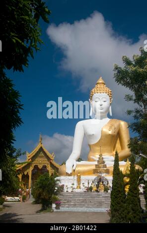 Thailand: Riesige Buddha-Statue mit Blick auf das Chiang Mai-Tal, Wat Phrathat Doi Kham, Chiang Mai. Wat Phrathat Doi Kham oder ‘Tempel des Goldenen Berges’, befindet sich in Tambon Mae Hia, etwa 10 km südlich der Altstadt von Chiang Mai, im schutze von Doi Suthep. Tempelrekorde behaupten, dass der Tempel über 1,300 Jahre ‘bis 687 u.Z.’ zurückreicht, während der Zeit vor LAN Na, als die Region von der einheimischen Animstin Lawa bewohnt wurde. Chiang Mai (was „neue Stadt“ bedeutet), manchmal auch als „Chiengmai“ oder „Chiangmai“ geschrieben, ist die größte und kulturell bedeutsamste Stadt im Norden Thailands. Stockfoto