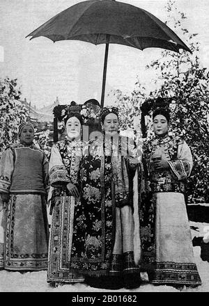 China: Kaiserin Dowager Cixi (29. November 1835 - 15. November 1908) mit Gerichtsdienern c. 1905. Kaiserin Dowager Cixi, persönlicher Name Xingzhen, war die Konkubine des Imperators Xianfeng. Vom Mandschu-Yehe-Nara-Clan war sie eine starke und charismatische Figur, die von 1861 bis 1908 47 Jahre lang de facto die Herrscherin der Qing-Dynastie wurde. Ihr Sohn wurde der Tongzhi-Kaiser, und sie regierte an seiner Stelle als Regentin neben Kaiserin Dowager Ci'an. Sie konsolidierte ihre Kontrolle, indem sie ihren Neffen nach dem Tod ihres Sohnes als Kaiser Guangxu einsetzte. Ihr Vermächtnis wird heftig diskutiert. Stockfoto