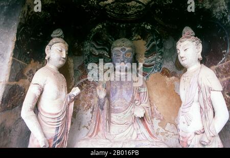 China: Buddha flankiert von Bodhisattvas, Maiji Shan Grotten, Tianshui, Provinz Gansu. Maijishan Shiku (Maiji Shan Grotten) sind eine der vier wichtigsten buddhistischen Tempelgruppen Chinas (die anderen sind Datong, Luoyang und die Mogao-Höhlen in Dunhuang). Ausgehend von den Dynastien Nördlicher Wei (386-535) und Nördlicher Zhou (557-81) schnitten Buddhisten Höhlen in die Seiten eines roten Ausschnitts, der aus den umliegenden Laubhügeln aufsteigt. Figuren des Buddha, von Bodhisattvas und Schülern wurden in härtere Felsen gehauen, die von anderswo hergebracht wurden, und in den Höhlen installiert. Stockfoto