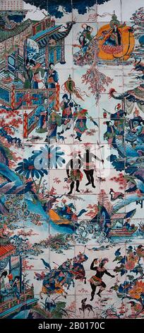 China/Afrika: Kachel-tableau zeigt mehrere chinesische Kaufleute und Adlige, die sich in einem afrikanischen Dorf, c.. 1700. Eine fast ausschließlich traditionelle chinesische Szene dreht sich um zwei robuste afrikanische Dorfbewohner, die in Röcken und Kopfbedeckungen gekleidet sind und Speere halten. Die Afrikaner scheinen amüsiert zu sein, wahrscheinlich neugierig auf den Anblick so vieler reich gekleideter chinesischer Männer und Frauen, Pagoden, Pavillons, chinesischer Laternen, einer Bambusbrücke, Eine chinesische Gondel und sogar ein schwebender Buddha am Himmel. In der unteren Hälfte des Gemäldes tanzt eine afrikanische Frau. Stockfoto