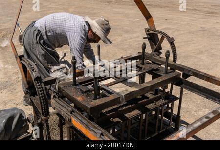 Shahin Dezh, Iran - 15. Mai 2019: Ein Arbeiter, der mit einer Maschine und einem Zement Ziegelsteine macht, Iran. Stockfoto