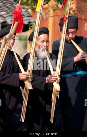 China: Miao-Männer spielen das Lusheng, ein traditonales Miao-Instrument, im Dorf Langde Shang, südöstlich von Kaili, Provinz Guizhou. Der Lusheng (auch lu sheng geschrieben; in der Hmong-Sprache Qeej und ausgeprägte Gaeng) ist ein chinesisches Musikinstrument mit mehreren Bambuspfeifen, die jeweils mit einem freien Rohr ausgestattet sind, das in einem langen Blasrohr aus Hartholz montiert ist. Es hat meistens fünf oder sechs Pfeifen mit unterschiedlichen Tonhöhen und ist somit ein polyphones Instrument. Es ist in Größen von sehr klein bis zu mehreren Metern Länge erhältlich. Stockfoto