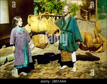 Japan: Großmutter und Enkelin verkaufen Körbe von einer Stange. Foto von T. Enami (1859-1929), c. 1910. T. Enami (Enami Nobukuni) war der Handelsname eines berühmten Meiji-Fotografen. Der T. seines Handelsnamens soll für Toshi gestanden haben, obwohl er ihn nie auf einem persönlichen oder geschäftlichen Dokument geschrieben hat. Geboren in Edo (heute Tokio) während der Bakumatsu-Ära, war Enami zuerst Schüler und dann Assistent des bekannten Fotografen und Umgangssprache, Ogawa Kazumasa. Enami zog nach Yokohama und eröffnete 1892 ein Studio in der Benten-dōri (Benten Street). Stockfoto