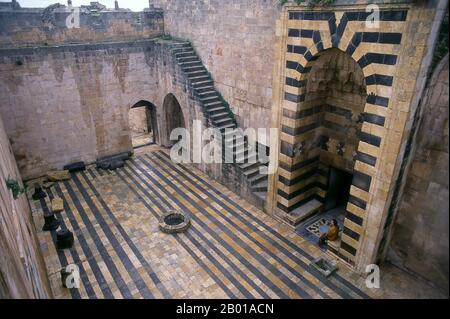 Syrien: Innenhof innerhalb der Zitadelle von Aleppo. Die Zitadelle von Aleppo ist ein großer mittelalterlicher befestigter Palast im Zentrum der Altstadt von Aleppo im Norden Syriens. Es gilt als eines der ältesten und größten Schlösser der Welt. Die Nutzung des Zitadellenhügels geht mindestens auf die Mitte des 3.. Jahrtausends v. Chr. zurück. Später von vielen Zivilisationen einschließlich der Griechen, Byzantiner, Ayyubids und Mamelukes besetzt, wird angenommen, dass der Großteil der Konstruktion, wie sie heute steht, aus der Ayyubid-Zeit stammt. Stockfoto