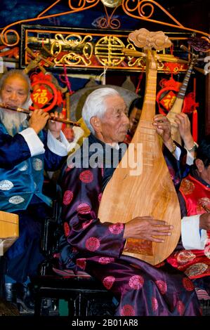 China: Ein Mann pflückt eine Pipa oder chinesische Laute, das Naxi (Nakhi) Folk Orchestra, die Naxi-Orchesterhalle, Lijiang Old Town, Provinz Yunnan. Naxi-Musik ist 500 Jahre alt und hat mit ihrer Mischung aus literarischen Texten, poetischen Themen und musikalischen Stilen der Tang-, Song- und Yuan-Dynastien sowie einigen tibetischen Einflüssen einen eigenen, einzigartigen Stil und Züge entwickelt. Es gibt drei Hauptstile: Baisha, Dongjing und Huangjing, alle mit traditionellen chinesischen Instrumenten. Die Naxi oder Nakhi sind eine ethnische Gruppe, die am Fuße des Himalaya im Nordwesten der Provinz Yunnan lebt. Stockfoto