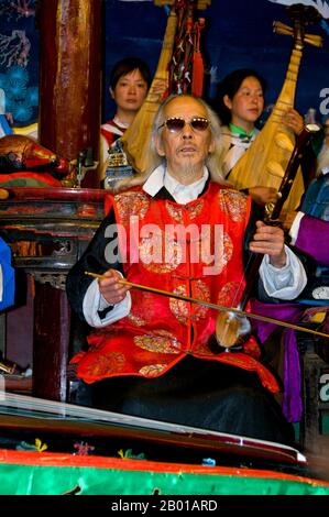 China: Ein Mann spielt eine Banhu, das Naxi (Nakhi) Folk Orchestra, die Naxi-Orchesterhalle, Lijiang Old Town, Provinz Yunnan. Naxi-Musik ist 500 Jahre alt und hat mit ihrer Mischung aus literarischen Texten, poetischen Themen und musikalischen Stilen der Tang-, Song- und Yuan-Dynastien sowie einigen tibetischen Einflüssen einen eigenen, einzigartigen Stil und Züge entwickelt. Es gibt drei Hauptstile: Baisha, Dongjing und Huangjing, alle mit traditionellen chinesischen Instrumenten. Die Naxi oder Nakhi sind eine ethnische Gruppe, die am Fuße des Himalaya im Nordwesten der Provinz Yunnan lebt. Stockfoto