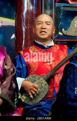China: Ein Mann spielt einen Sanxian, das Naxi (Nakhi) Folk Orchestra, die Naxi-Orchesterhalle, Lijiang Old Town, Provinz Yunnan. Naxi-Musik ist 500 Jahre alt und hat mit ihrer Mischung aus literarischen Texten, poetischen Themen und musikalischen Stilen der Tang-, Song- und Yuan-Dynastien sowie einigen tibetischen Einflüssen einen eigenen, einzigartigen Stil und Züge entwickelt. Es gibt drei Hauptstile: Baisha, Dongjing und Huangjing, alle mit traditionellen chinesischen Instrumenten. Die Naxi oder Nakhi sind eine ethnische Gruppe, die am Fuße des Himalaya im Nordwesten der Provinz Yunnan lebt. Stockfoto