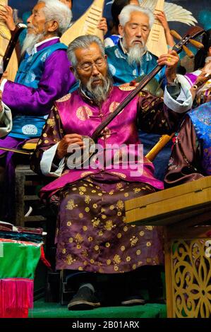 China: Ein Mann spielt einen Sanxian, das Naxi (Nakhi) Folk Orchestra, die Naxi-Orchesterhalle, Lijiang Old Town, Provinz Yunnan. Naxi-Musik ist 500 Jahre alt und hat mit ihrer Mischung aus literarischen Texten, poetischen Themen und musikalischen Stilen der Tang-, Song- und Yuan-Dynastien sowie einigen tibetischen Einflüssen einen eigenen, einzigartigen Stil und Züge entwickelt. Es gibt drei Hauptstile: Baisha, Dongjing und Huangjing, alle mit traditionellen chinesischen Instrumenten. Die Naxi oder Nakhi sind eine ethnische Gruppe, die am Fuße des Himalaya im Nordwesten der Provinz Yunnan lebt. Stockfoto