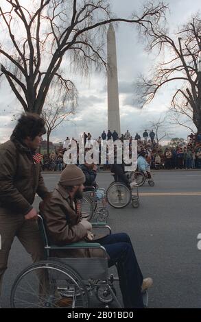 USA: Behinderte Veteranen im Rollstuhl passieren das Washington Monument während der Widmungsparade für das Vietnam Veterans Memorial. Foto von Mickey Sanborn (18. Februar 1943 - 21. Januar 2017, gemeinfrei) 1982. Der zweite Indochina-Krieg, in Amerika als Vietnamkrieg bekannt, war ein militärischer Konflikt aus der Zeit des Kalten Krieges, der sich in Vietnam, Laos und Kambodscha vom 1. November 1955 bis zum Fall Saigons am 30. April 1975 ereignete. Dieser Krieg folgte dem ersten Indochina-Krieg und wurde zwischen Nordvietnam, unterstützt von seinen kommunistischen Verbündeten, und der Regierung von Südvietnam, unterstützt von den USA, geführt Stockfoto