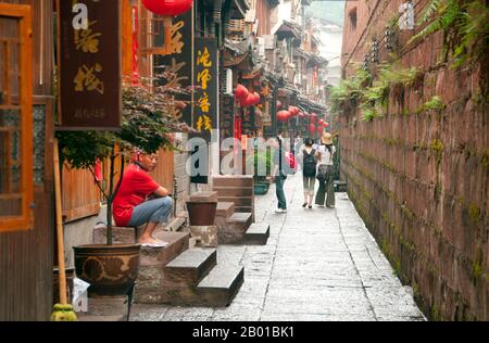 China: Alte Häuser dicht bis zur alten Stadtmauer, Fenghuang, Provinz Hunan. Fenghuang ist Chinesisch für Phoenix und bezieht sich auf den mythischen heiligen feuervogel, der in den Mythologien der Peter, Griechen, Römer, Ägypter, Chinesen, Und (nach Sanchuniathon) die Phönizier. Die Legende besagt, dass zwei Phönixe, die die Stadt entdeckten, einige Zeit über dem Kopf schwebten, bevor sie widerwillig wegflogen. Die Stadt Fenghuang ist eine gut erhaltene antike Stadt, die angeblich aus dem Jahr 248 v. Chr. stammt. Hier leben die Minderheiten Miao und Tujia. Stockfoto