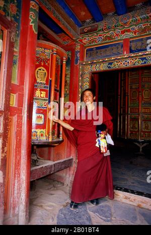 China: Ein junger tibetischer buddhistischer Mönch dreht ein großes Gebetsrad, Labrang Kloster, Xiahe, Provinz Gansu. Labrang Kloster ist eines der sechs großen Klöster der Gelug (Gelber Hut) Schule des tibetischen Buddhismus. Sein formaler Name ist Gandan Shaydrup Dargay Tashi Gyaysu Khyilway Ling, allgemein bekannt als Labrang Tashi khyil oder einfach Labrang. Das Kloster wurde 1709 von der ersten Jamyang Zhaypa, Ngawang Tsondru, gegründet. Es ist die wichtigste Klosterstadt des tibetischen Buddhismus außerhalb der tibetischen Autonomen Region. Stockfoto