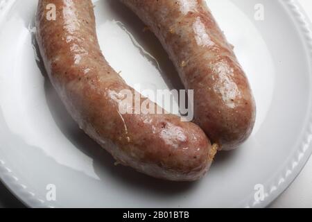 Studio-Schuss von typisch slowenischer, gebackener Wurst (nach dem Kochen im Wasser) auf einem weißen Teller Stockfoto