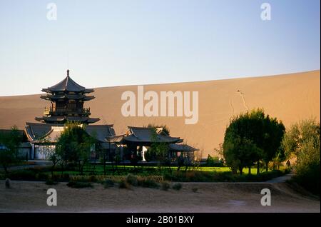 China: Tempel neben den singenden Sanddünen von Mingsha Shan (Mingsha Hills) in der Kumtagh Wüste, Provinz Gansu. Mingsha Shan (Singende Sanddünen) liegen etwa 4km südlich von Dunhuang. Sie sind die größten und eindrucksvollsten Sanddünen in China. Die Hauptdünen erheben sich zwischen 250m und 300m. Sie werden ‘Singing Sands’ genannt, weil die sich verschiebenden Sandkörner bei starken Winden ein brummendes Geräusch verursachen. Die Kumtagh-Wüste ist ein Teil der Taklamakan-Wüste, die östlich-südöstlich der Wüste Lop liegt. Stockfoto