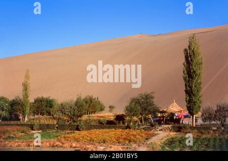 China: Die singenden Sanddünen von Mingsha Shan (Mingsha Hills) in der Kumtagh-Wüste, Provinz Gansu. Mingsha Shan (Singende Sanddünen) liegen etwa 4km südlich von Dunhuang. Sie sind die größten und eindrucksvollsten Sanddünen in China. Die Hauptdünen erheben sich zwischen 250m und 300m. Sie werden ‘Singing Sands’ genannt, weil die sich verschiebenden Sandkörner bei starken Winden ein brummendes Geräusch verursachen. Die Kumtagh-Wüste ist ein Teil der Taklamakan-Wüste, die östlich-südöstlich der Wüste Lop liegt. Stockfoto