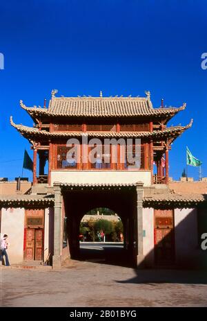 China: Eine alte Karawanserei, jetzt ein Museum, neben den Sanddünen von Mingsha Shan (Mingsha Hills) in der Kumtagh Wüste, Dunhuang, Provinz Gansu. Haltungsplätze, im Allgemeinen Karawanserei in türkischer und persischer Sprache gestylt, wurden von Herrschern gegründet, um den Handel zu fördern und zu schützen, der ihre Königreiche bereicherte. Idealerweise waren es Gasthäuser am Straßenrand, die einen Tag voneinander entfernt standen, wo Reisende essen, schlafen und sich von der Tagesreise erholen konnten, mit ihren Tieren sicher angebunden, bewässert und gefüttert und ihren wertvollen Gütern sicher in Mauern. Stockfoto