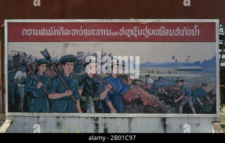 Laos: Politisches Plakat im Stil des revolutionären Sozialistischen Realismus auf den Straßen von Vientiane. Sozialistischer Realismus ist ein Stil realistischer Kunst, der in der Sowjetunion entwickelt wurde und in anderen kommunistischen Ländern zu einem dominanten Stil wurde. Der sozialistische Realismus ist ein teleologisch orientierter Stil, der die Ziele des Sozialismus und Kommunismus fördern soll. Obwohl verwandt, sollte sie nicht mit dem sozialen Realismus verwechselt werden, einer Art Kunst, die Themen von sozialem Interesse realistisch darstellt. Im Gegensatz zum sozialen Realismus verherrlicht der sozialistische Realismus oft die Rolle der Armen. Stockfoto