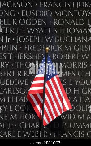 USA: Eine kleine amerikanische Flagge steht gegen die Vietnam Veterans Memorial Wall, Washington DC. Foto von William D. Moss (öffentlich zugänglich), 4. Mai 2010. Das Vietnam Veterans Memorial ist ein nationales Denkmal in Washington, D.C. Es ehrt US-Dienstmitglieder der US-Streitkräfte, die im Vietnamkrieg gekämpft haben, Dienstmitglieder, die im Dienst in Vietnam/Südostasien gestorben sind, Und jene Dienstmitglieder, die während des Krieges nicht berücksichtigt wurden (in Aktion vermisst). Stockfoto