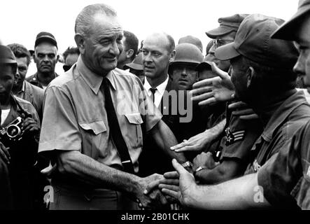 Vietnam: Präsident Lyndon B. Johnson begrüßt amerikanische Truppen in Saigon, 1966. Der zweite Indochina-Krieg, in Amerika als Vietnamkrieg bekannt, war ein militärischer Konflikt aus der Zeit des Kalten Krieges, der sich in Vietnam, Laos und Kambodscha vom 1. November 1955 bis zum Fall Saigons am 30. April 1975 ereignete. Dieser Krieg folgte dem ersten Indochina-Krieg und wurde zwischen Nordvietnam, unterstützt von seinen kommunistischen Verbündeten, und der Regierung von Südvietnam, unterstützt von den USA und anderen antikommunistischen Nationen, geführt. Die US-Regierung betrachtete die Beteiligung am Krieg als eine Möglichkeit, eine kommunistische Übernahme von Südvietnam zu verhindern. Stockfoto