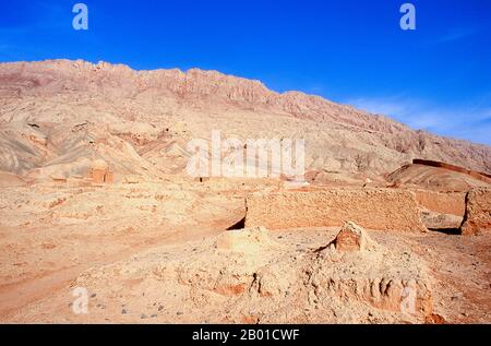 China: Ein Friedhof neben dem Dorf Tuyoq in der Nähe von Turpan, Provinz Xinjiang. Tuyoq oder Tuyugou ist ein altes Oasendorf in der Taklamakan Wüste, 70 km östlich von Turpan in einem üppigen Tal, das in die Flaming Mountains schneidet, mit einer gut erhaltenen uigurischen Ausrichtung. Es ist berühmt für seine kernlosen Trauben und eine Reihe von alten buddhistischen Meditationshöhlen in der Nähe mit Fresken, die bekannteste sind die Bezeklik Thousand Buddha Höhlen. Stockfoto