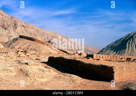 China: Ein Friedhof neben dem Dorf Tuyoq in der Nähe von Turpan, Provinz Xinjiang. Tuyoq oder Tuyugou ist ein altes Oasendorf in der Taklamakan Wüste, 70 km östlich von Turpan in einem üppigen Tal, das in die Flaming Mountains schneidet, mit einer gut erhaltenen uigurischen Ausrichtung. Es ist berühmt für seine kernlosen Trauben und eine Reihe von alten buddhistischen Meditationshöhlen in der Nähe mit Fresken, die bekannteste sind die Bezeklik Thousand Buddha Höhlen. Stockfoto