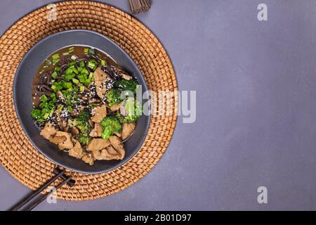 Soba Nudel mit Teriyaki-Huhn und Brokkoli auf grauem Steintisch Stockfoto