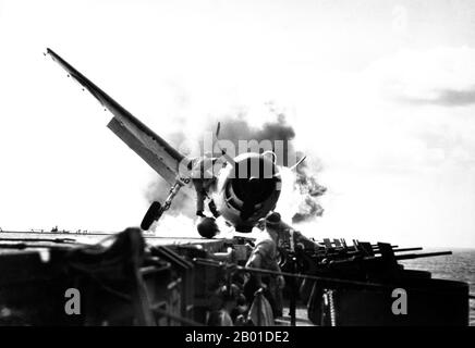 USA/Japan: Ein USAF F6F-3 Crash landete auf dem Deck der USS Enterprise, 10. November 1943. Crash Landung von F6F auf dem Flugdeck der USS Enterprise während des Angriffs auf Makin Island. LT. Walter Chewning, Katapult-Offizier, klammert die Seite des Flugzeugs hoch, um dem Piloten, Fähnrich Byron Johnson, aus dem brennenden Cockpit zu helfen. Stockfoto