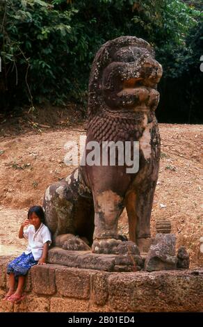 Kambodscha: Ein junges Mädchen sitzt unter einem singha (mythischer Löwe) am Fuß von Phnom Bakheng. Wenige hundert Meter hinter dem Südtor von Angkor Thom erhebt sich der Hügel von Phnom Bakheng 67 Meter (218 Fuß) über die umliegenden Ebenen. Dies ist ein idealer Ort, um die fernen Türme von Angkor Wat bei Sonnenuntergang zu sehen. Auf der Ostseite des Hügels bietet eine steile und heimtückische Treppe eine schnelle, aber schwierige Möglichkeit zum Aufstieg. Alternativ, und viel einfacher, führt ein gewundener Elefantenpfad über die Südseite des Hügels zum Gipfel. Phnom Bakheng in Angkor, Kambodscha, ist ein hinduistischer Tempel. Stockfoto