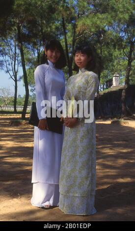 Vietnam: Zwei Studenten in traditionellem vietnamesischen AO dai („langes Kleid“). Der Ao dai (Vietnamesisch: áo dài) ist ein vietnamesisches Nationalkostüm, heute am häufigsten für Frauen. In ihrer derzeitigen Form ist es eine eng anliegende Seidentunika, die über Pantaloons getragen wird. Das Wort wird im Norden als ow-zye und im Süden als ow-yai ausgesprochen und übersetzt als "Long dress". Der Name áo dài wurde ursprünglich auf das Kleid verwendet, das im 18. Jahrhundert am Hof der Nguyễn-Herren in Huế getragen wurde. Aus diesem Outfit entwickelte sich das áo ngũ thân, ein fünfteiliges, aristokratisches Kleid, das im 19. Und frühen 20. Jahrhundert getragen wurde. Stockfoto